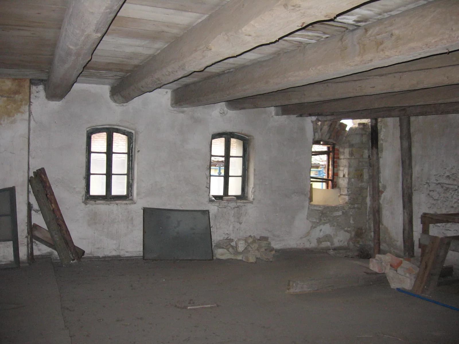 Místnost s okny a trámovým stropem. Fotografie majitelů pivovaru.
